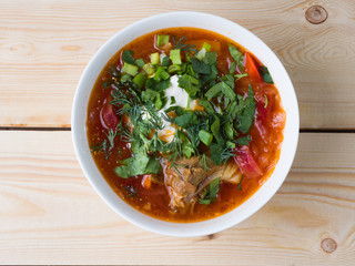 Borsch with sour cream in a white bowl on a wooden background. Top view