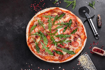 Fresh pizza baked in oven with arugula, salami, cherry tomatoes and mozzarella
