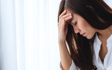 Fototapeta premium A sad and stressed young asian woman sitting alone in bedroom