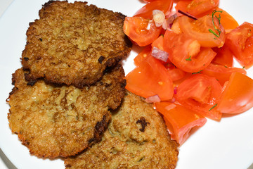 Polish potato pancakes with chopped tomato salad. Placki Ziemniaczane Recipe
