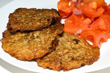 Polish potato pancakes with chopped tomato salad. Placki Ziemniaczane Recipe