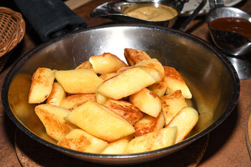 Fried potato dumplings served in a pan with sausages, fried onion, cheese sauce.
