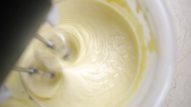 Close-up of a mixer making cream for preparing delicious home-made baking, view from above.