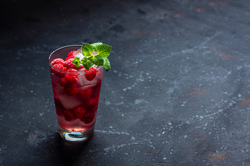 Raspberry alcoholic cocktail with liqueur, vodka, ice and mint on a dark background. Raspberry...