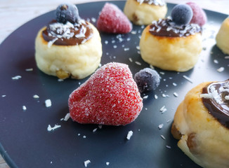 Cheesecakes with chocolate sauce with strawberries and black currant