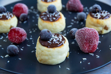 Cheesecakes with chocolate sauce with strawberries and black currant