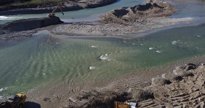 Collaborating Water escavator working inside Arno river near Sieci town, Pontassieve, to avoid another Florence disaster flood afer latest November rainy long season. Sunny day Winter, Tuscany. Italy
