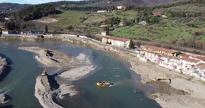 Aerial Water escavators working inside Arno river near Sieci town, Pontassieve, to avoid another Florence disaster flood afer latest November rainy long season. Sunny day Winter, Tuscany. Italy
