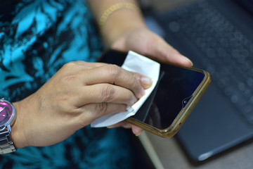 Cleaning mobile phone to eliminate germs,Covid-19. Woman disinfecting phone with antiseptic wet wipe.