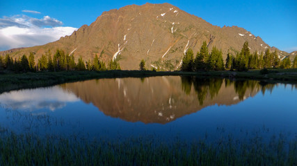 Fototapeta na wymiar High mountain lake reflecting jagged peaks
