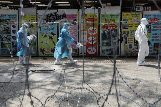 Medical workers wearing protective suits pass by barbed wire at the red zone under enhanced lockdown, amid the coronavirus disease (COVID-19) outbreak, in Petaling Jaya