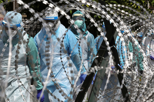 Medical workers wearing protective suits pass by barbed wire at the red zone under enhanced lockdown, amid the coronavirus disease (COVID-19) outbreak, in Petaling Jaya