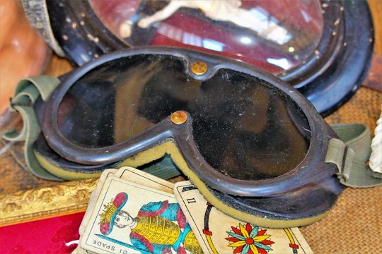 Milan, Italy, 2017.05.21 evocative image of old biker / aviator glasses on top of old playing 
cards at a vintage market