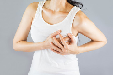 young woman in white vest , grabbing an chest, She has heart disease. Health Care Concept.