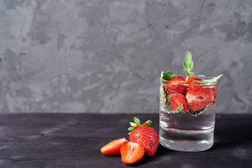 Infused water with strawberry and mint in sparkling glasses on wood black table background, copy space. Cold summer drink. Mineral water