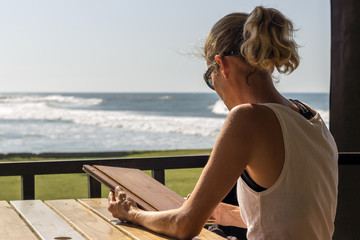 woman looking at a menu at a coffee shop with the ocean in the background