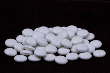 White pills on a dark background. Subject macro photography.