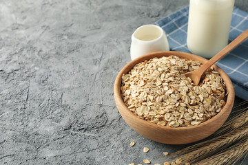 Composition with oatmeal flakes and milk on gray background. Cooking breakfast