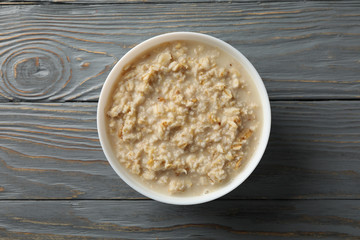 Bowl with oatmeal porridge on wooden background