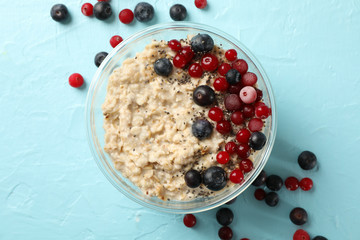 Bowl with oatmeal porridge and fruits on blue background