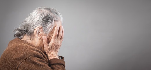 Sad elderly woman covering her face.