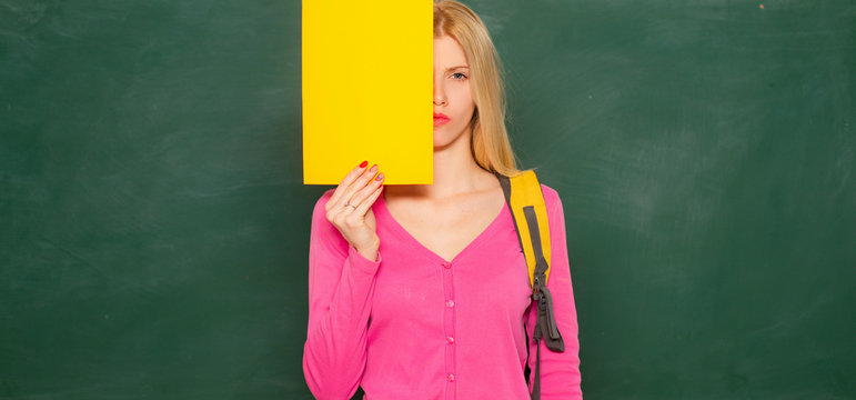 Young female college student in class. Portrait of a school girl posing with backpack and school supplies. Smiling happy female college student.