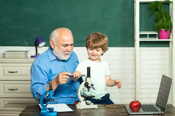 Portrait of grandfather and grandson on blackboard in classroom - generation people concept. Portrait of confident old male teacher. Boy from elementary school at the school yard.