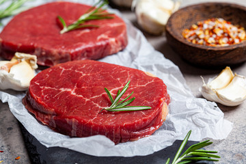 Raw beef meat on slate board with spices. Raw beef steaks, dark gray background.