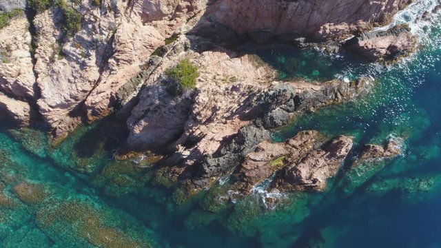 AERIAL DRONE TOP DOWN ZENITHAL SMOOTH SIDE SHOT OF MEDITERRANEAN ROCKY SEA SIDE WITH STUNNING CLEAR BLUE TURQUOISE WATER 