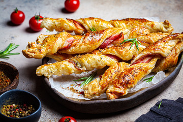 Crispy bread sticks with cheese, bacon and spices. Beer snacks. Dark background.