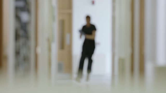Slow motion medical staff running through corridor to emergency out of focus