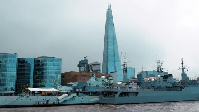 Floating on the river Thames in the business district in the City of Central London, UK. Skyline with iconic skyscrapers like the Shard or Tate Modern and the HMS Belfast, a WWII ship.