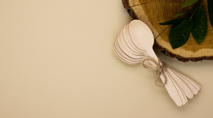 Eco wooden spoons for catering and street fast food on a beige background with a copy space. Cleanliness of the planet, care for nature and the concept of waste disposal