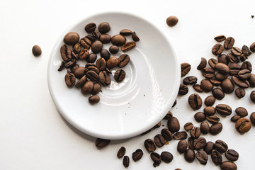 Coffee beans in white saucer and on white background. Top view.