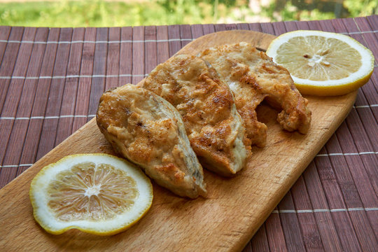 Pieces of fried fish with lemon wedges.