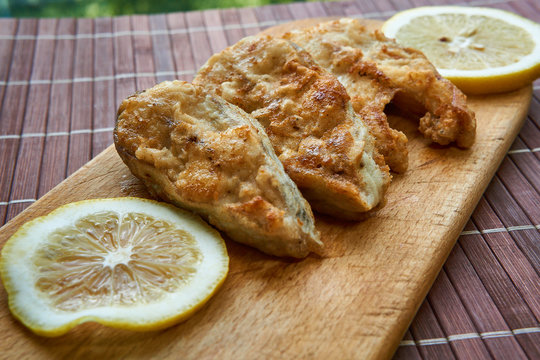 Pieces of fried fish with lemon wedges.