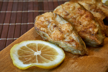 Pieces of fried fish with lemon wedges.