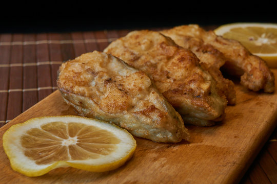 Pieces of fried fish with lemon wedges.