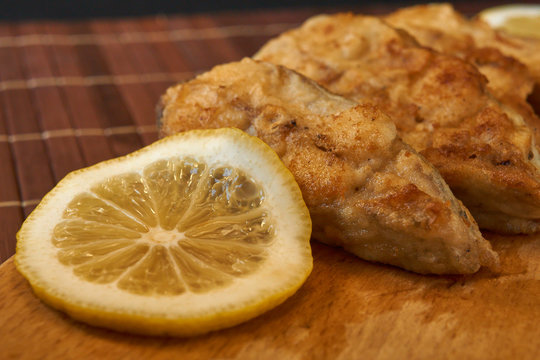 Pieces of fried fish with lemon wedges.