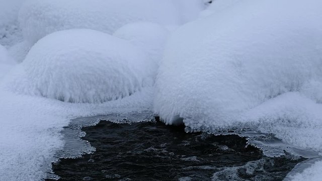 Stones with snow caps in the water of frozen river Pescherka in winter