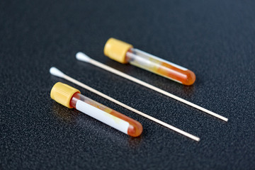 medicine, healthcare and pandemic concept - test tubes with blood plasma and cotton swabs on table