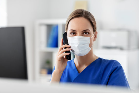 medicine, people and healthcare concept - female doctor or nurse wearing face protective medical mask for protection from virus disease with computer calling on phone at hospital