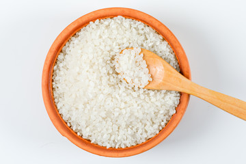 Fototapeta na wymiar Raw rice with wooden spoon in a wooden bowl on white background, flat lay.