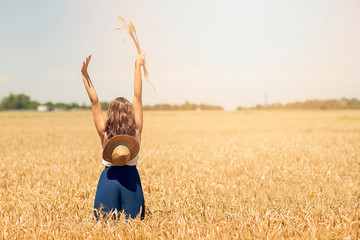 Happy woman enjoying the life in the field. Nature beauty, blue sky and field with golden wheat. Outdoor lifestyle. Freedom concept. Woman jump in summer field