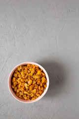 Golden Raisins in a Pink Bowl on a gray surface, top view. Flat lay, overhead, from above. Copy space.