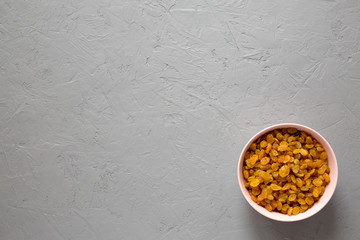 Golden Raisins in a Pink Bowl on a gray background, top view. Flat lay, overhead, from above.