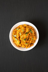 Homemade Chicken Tikka Masala in a white bowl on a black surface, top view. Flat lay, overhead, from above.
