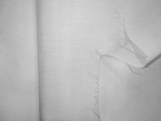 White texture of folded natural fabric with a crease and cut edge. Empty textured textile background