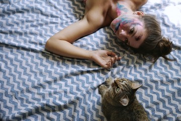 young woman lying on the bed with her cat