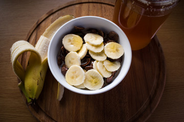 Cereals bowl with honey and banana on wooden background close up. Healthy lifestyle concept